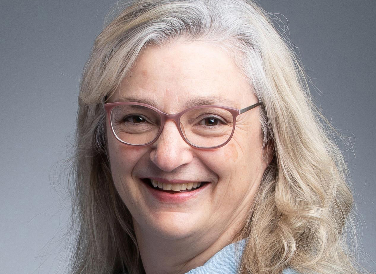 Headshot of Sandi Gauder. A smiling woman with long hair and glasses.
